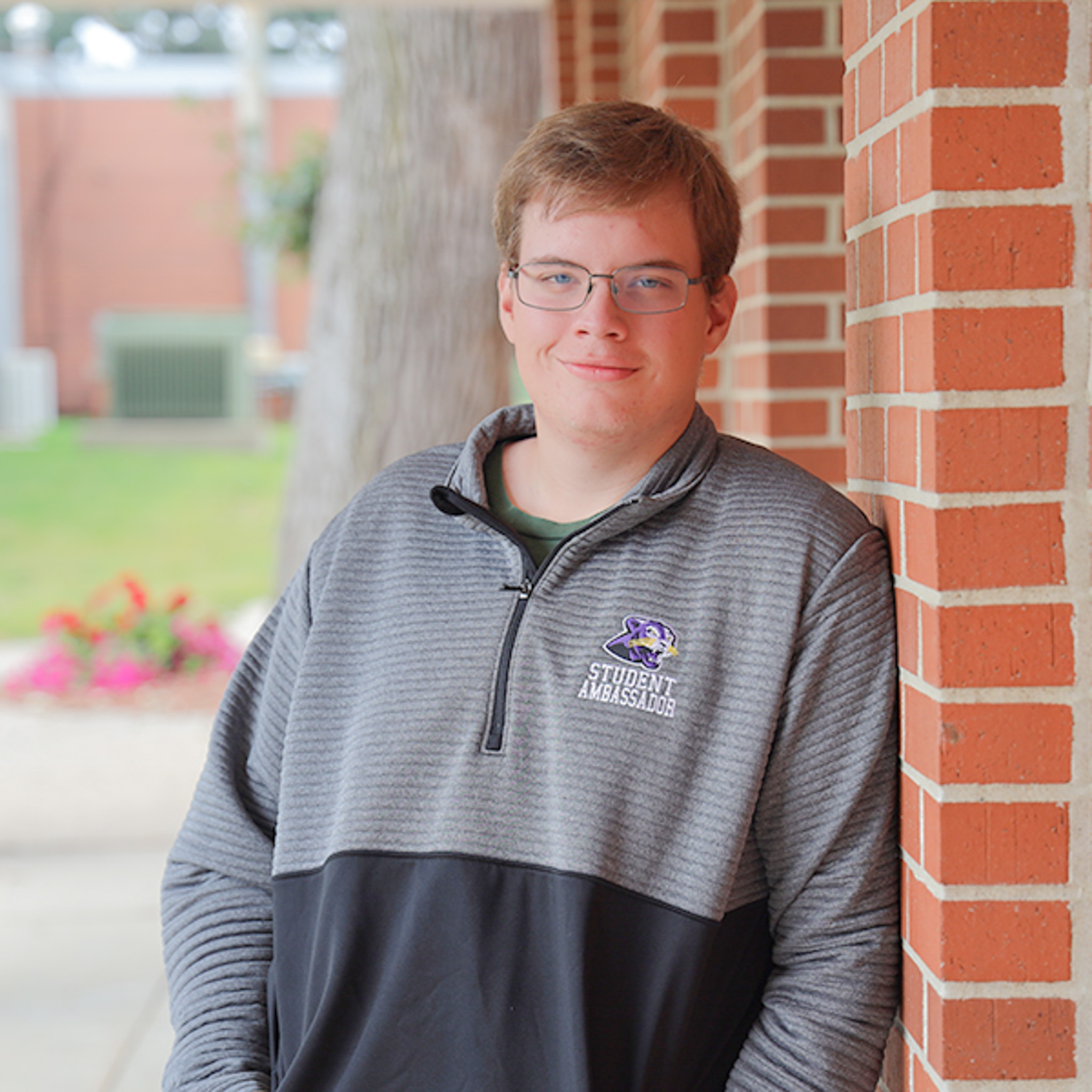 Justin leaning against Gentle Student Center building. 
