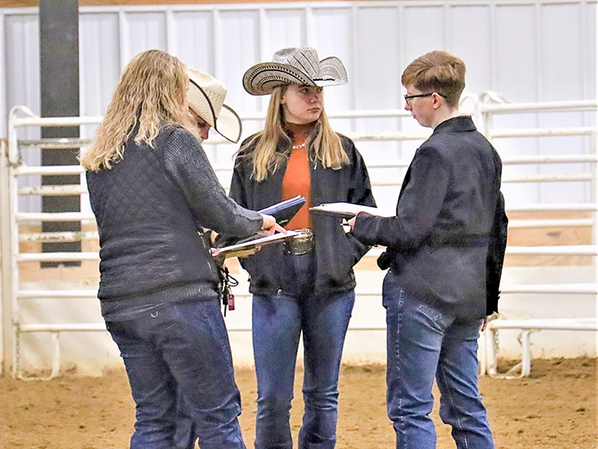 Studnets standing in arena with professor during a judging competition.