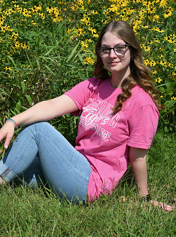 Emma Short sitting in the grass with yellow flowers behind her