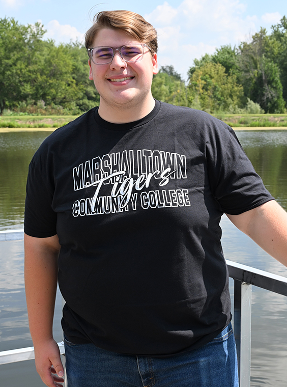 Jacen Wenger standing on the MCC campus smiling with the campus pond in the background