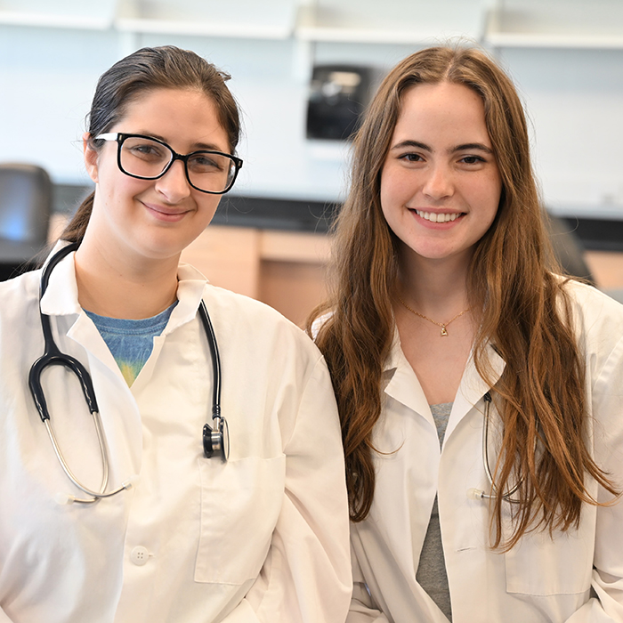 two female students in lab coats smiling