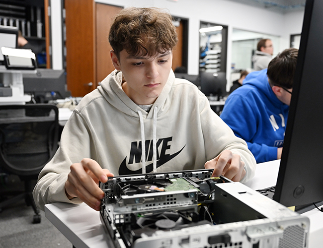 male student working on the inside of a computer