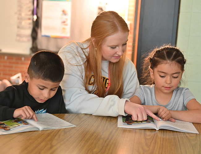 education student with two elementary students in school