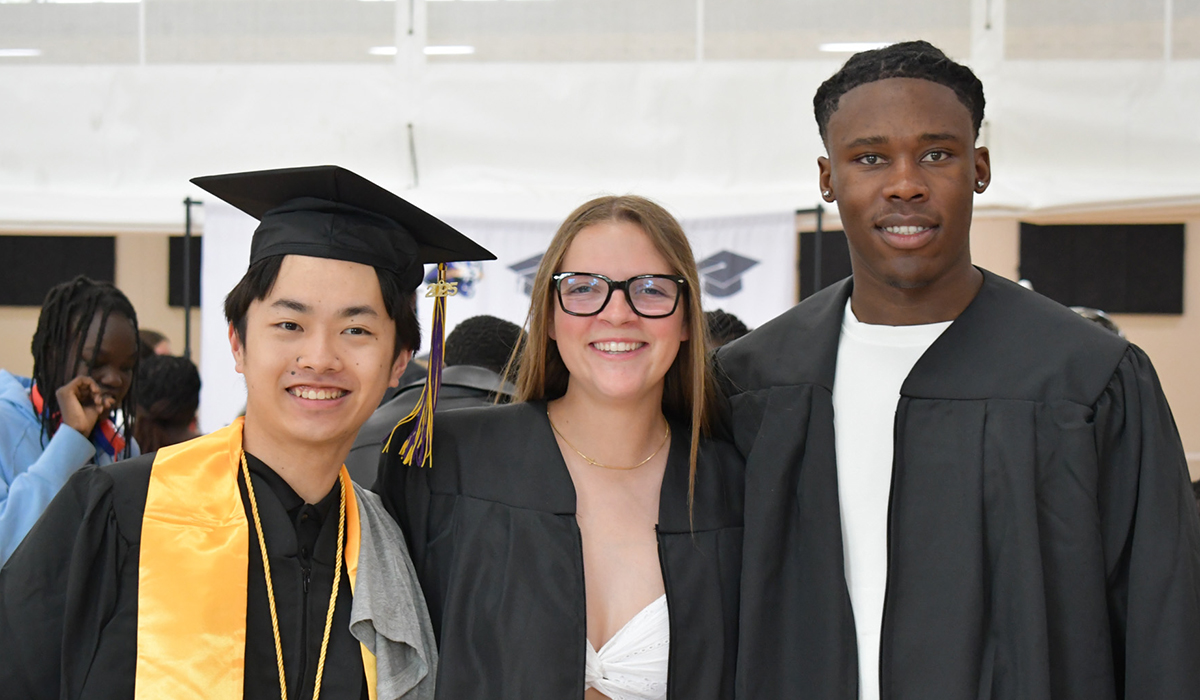 two male students and one female student in their grad caps and gowns
